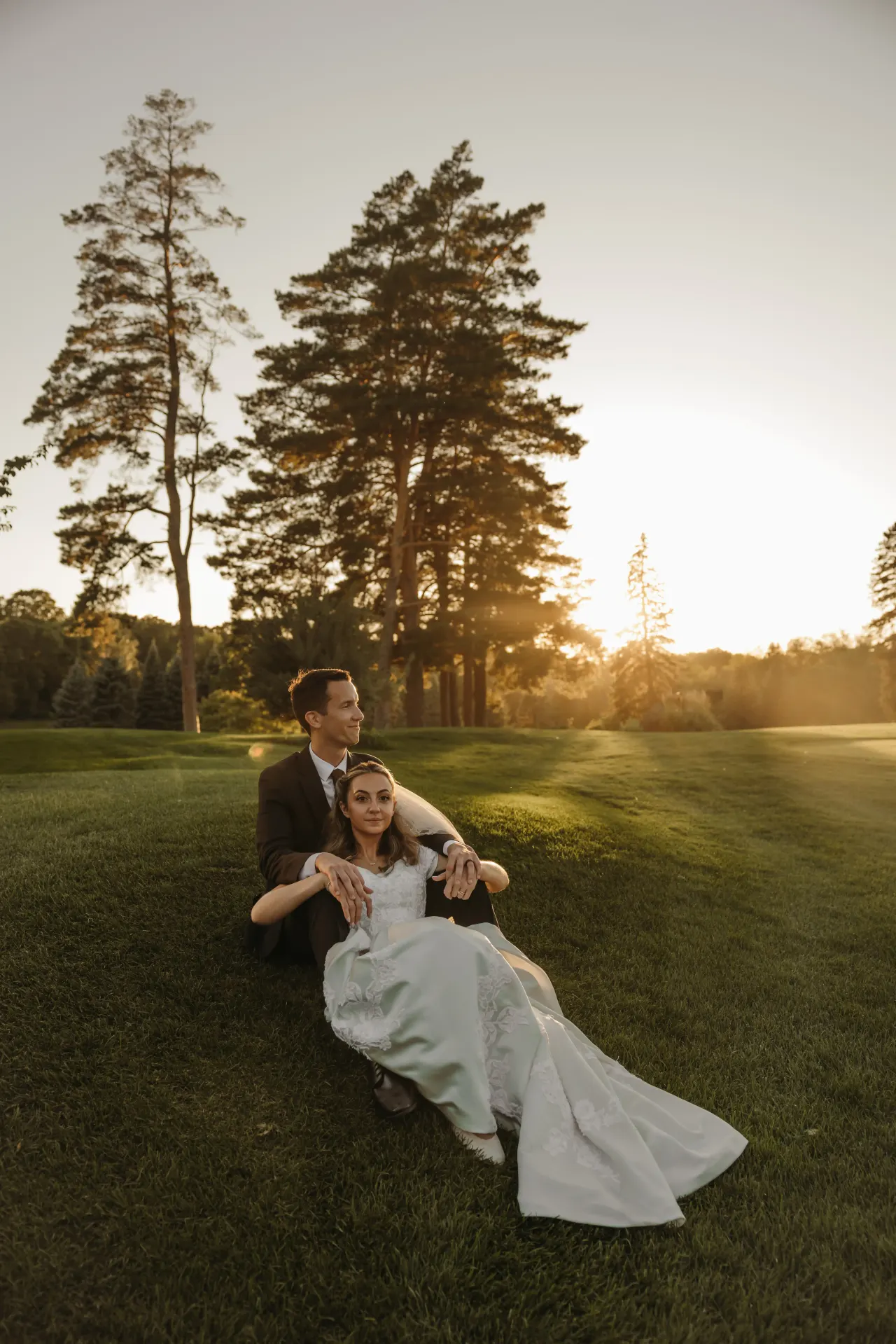 Couple sitting together on a fairway lawn as the sun sets through the pines — Minneapolis & Twin Cities wedding photography by Emma Ziegler, Honey Deww Photography (Minnesota)