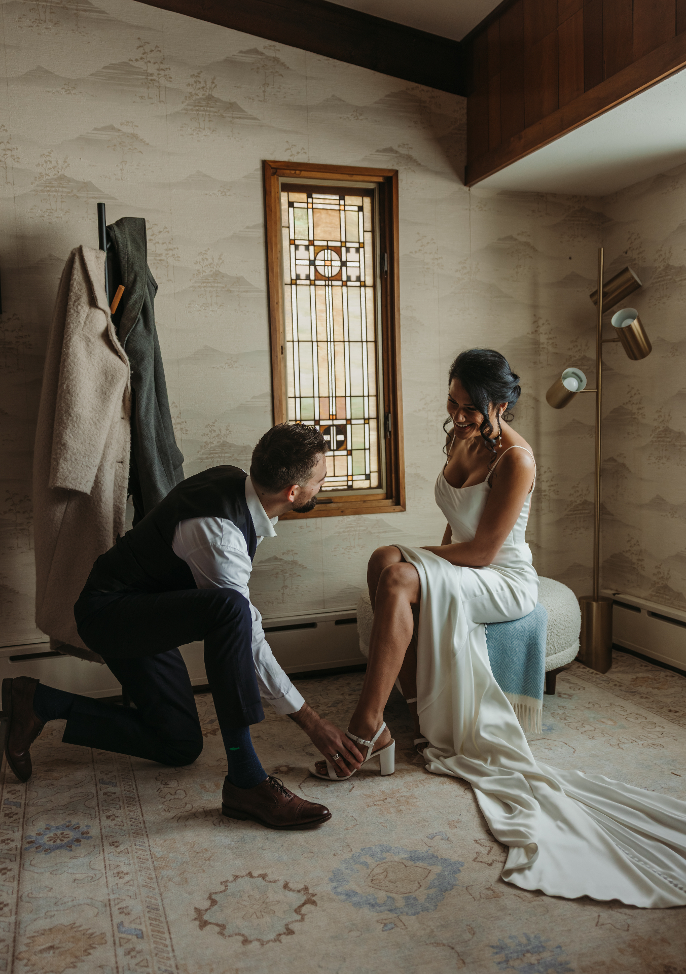 Groom helping bride with shoes in elegant room