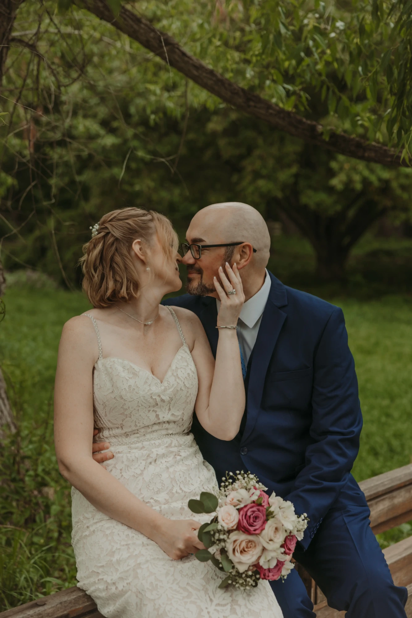 Couple sitting on the bridge rail under a willow, noses touching