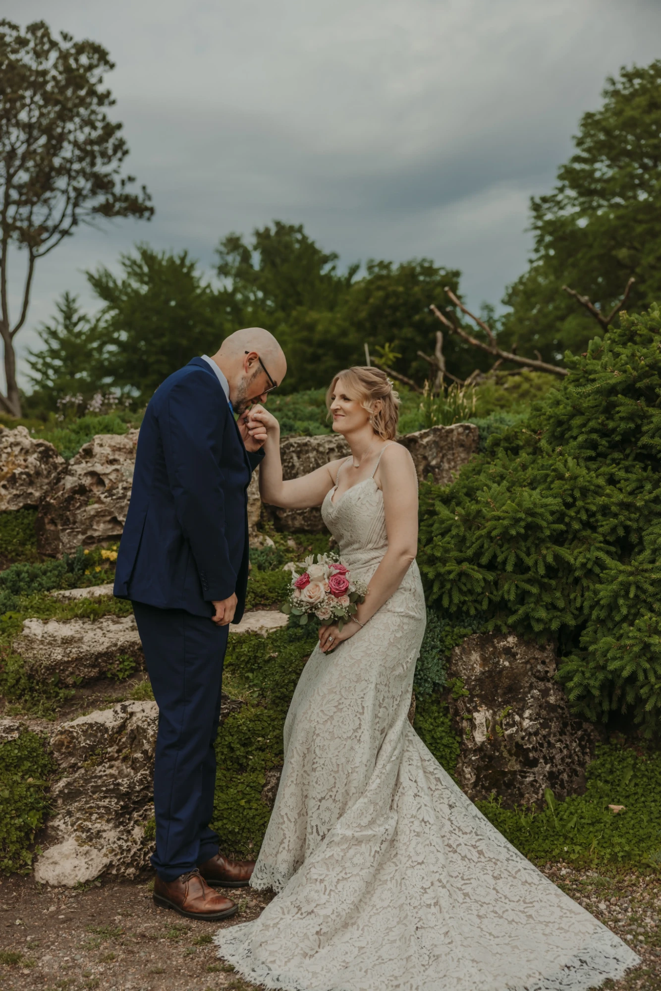 Groom kissing the bride's hand on stone steps